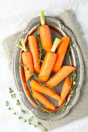Fresh organic raw sliced carrots with thyme on metal plateの写真素材