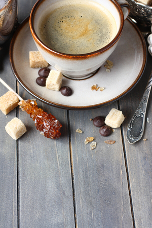 Cup of coffee, sugar cubes and chocolate drops on old wooden background with copy spaceの写真素材