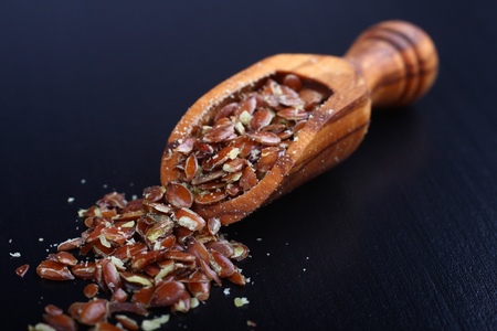 Broken flax seeds in wooden scoopsの写真素材