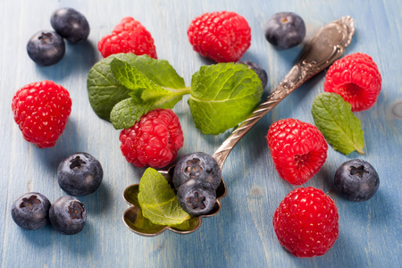 Berries on Blue Wooden Background. Summer or Spring Organic Berry over Wood. Raspberries, Blueberry, Vintage Spoon and Mint. Agriculture, Gardening, Harvest Conceptの写真素材