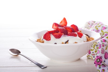 Yogurt with homemade granola or muesli and fresh strawberries for healthy morning breakfast, selective focus, over white. Healthy food background with copy space for text.の写真素材