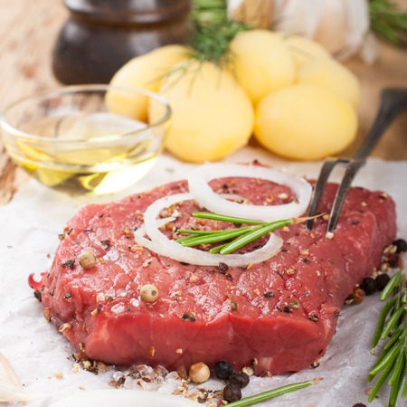 Stack of raw beef steaks and spices on old wooden background.  Healthy food concept. Selective focus.の写真素材