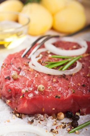 Stack of raw beef steaks and spices on old wooden background.  Healthy food concept. Selective focus.の写真素材