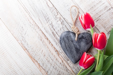 Valentines Day background with decorative heart and pink tulips on white old wooden planks with copy space for text. Valentine's Day concept. View from above.の写真素材