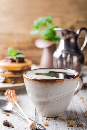 Cup coffee for breakfast with pancakes on old wooden background.の写真素材