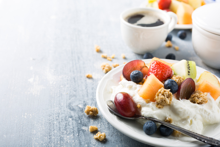 Breakfast, quark with granola, fruits and berries on light wooden background. Healthy food concept with copy space for text.の写真素材