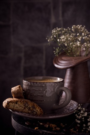 Coffee cup with cookies and coffee beans on dark rustic background with space for text. Toned.の写真素材