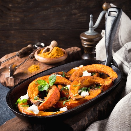 Roasted, baked pumpkin with addition aromatic herbs, goat cheese and mint. Healthy food concept with copy space.の写真素材