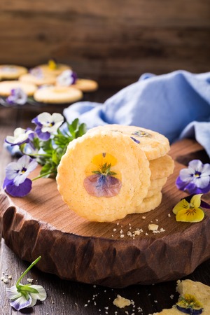 Homemade shortbread cookies with edible flowers on old wooden background. Holiday foodの写真素材