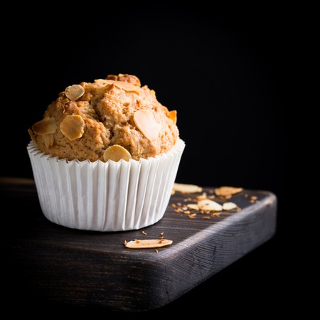 Delicious homemade coconut cinnamon muffin with almond flakes on black background. Healthy food concept with copy space.の写真素材