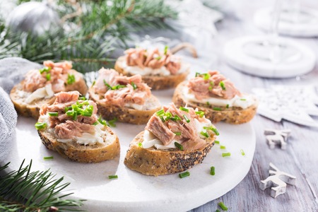 Slices of baguette with fresh tuna, cream cheese and chopped onion chives on marble board. Christmas themed dinner table.の写真素材