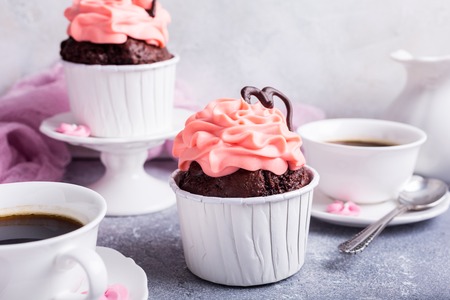Valentines and Mother Day, wedding greeting card with beautiful chocolate cupcake, pink cream and heart on gray stone background.の写真素材