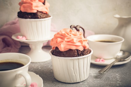 Beautiful chocolate cupcake, pink cream and heart on gray stone background. Valentines, Mother Day, wedding concept with copy space. Retro style toned.の写真素材