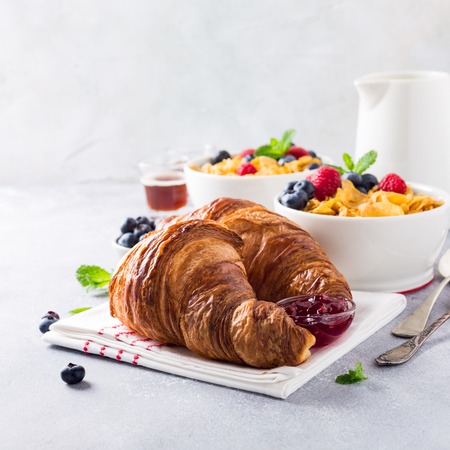 Croissants, corn flakes and berries on light gray background. Copy space. Healthy breakfast concept.の写真素材