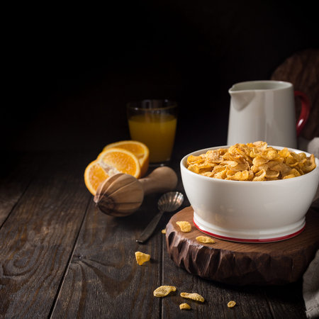 Corn flakes with milk on dark wooden background. Copy space. Helthy breakfast concept.