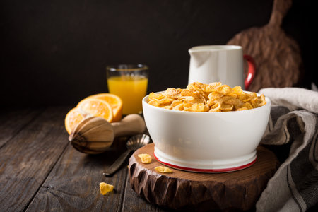 Corn flakes with milk on dark wooden background. Copy space. Helthy breakfast concept.