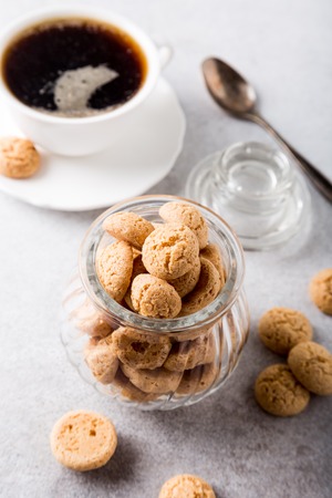 Amaretti cookies in glass pot with white cup of coffee on light gray background with copy space. High angle viewの写真素材