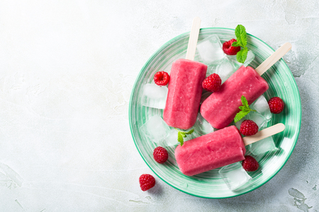 Homemade strawberry popsicles on green plate with ice, strawberries and mint. Healthy summer food concept with copy space. Top view.の写真素材