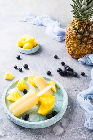 Pineapple popsicles with fresh blueberries on gray background. Healthy food concept. High angle view.の写真素材