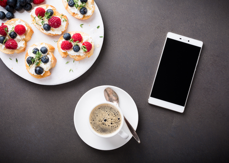 Cup of coffee with berry and goat cheese sandwiches, overhead shot, copy space.の写真素材