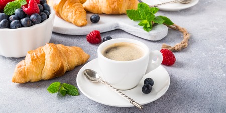 White cups of coffee and croissants on light gray background, selective focus. Healthy breakfast concept with copy space. Banner.の写真素材