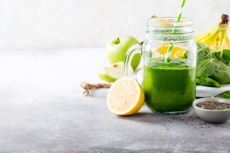Healthy breakfast with green smoothie in glass jar and ingredients. Detox, diet, healthy, vegetarian food concept with copy space.の写真素材