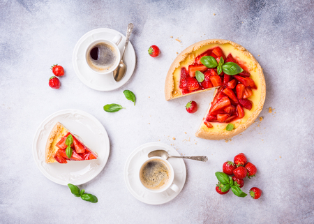 Overhead shot of cups of coffee, delicious homemade strawberry cheesecake and flowers on light gray background. Top view, flat lay.の写真素材