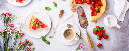 Overhead shot of cups of coffee, delicious homemade strawberry cheesecake and flowers on light gray background. Top view, flat lay. Banner.の写真素材