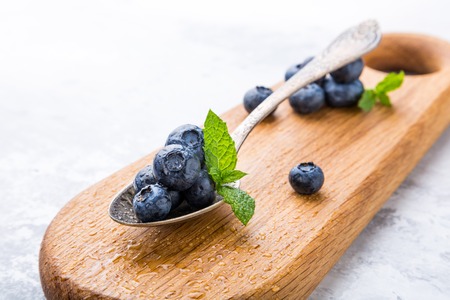 Fresh blueberries in vintage spoon on wooden cutting board. Healthy eating and nutrition concept with copy space.の写真素材
