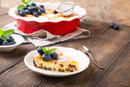 Piece of homemade cheesecake made from cottage cheese, decorated with blueberries and mint on wooden background. Healthy food concept with copy space.の写真素材
