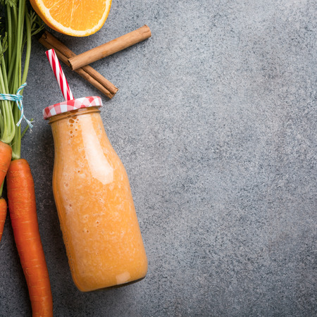 Healthy carrot smoothie with orange and cinnamon in glass bottle and ingredients. Detox, diet, healthy, vegetarian food concept with copy space. Top view.の写真素材