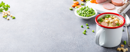 Delicious homemade pea soup with sausage and croutons in enamel mug. Healthy food concept with copy space.の写真素材