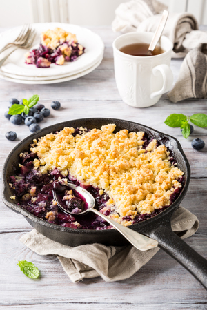 Coconut crumble in cast iron pan with fresh apples and blueberry. Healthy food concept.の写真素材