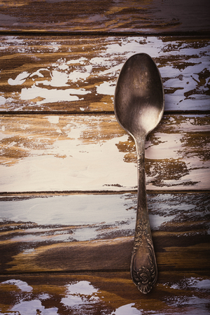 Metal spoon on old wooden grunge background. Retro style toned photo with copy space.の写真素材
