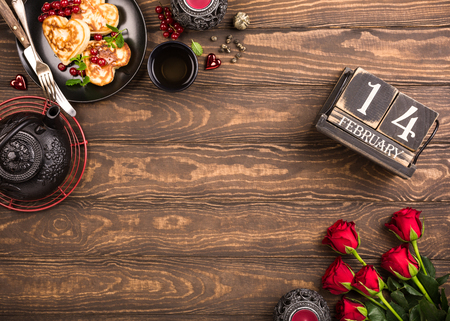 Valentines day background with green tea, black teapot, candles, roses and wooden calendar. Valentines day concept. Top view. Copy space.の写真素材