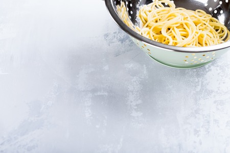 Fresh cooked spaghetti in stainless strainer on light background. Healthy food concept with copy space for text.の写真素材