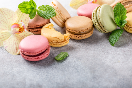 French assorted macarons with mint leaves on light gray concrete background. Holidays food concept with copy space.の写真素材