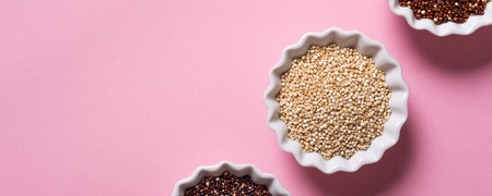 Top view of assorted Quinoa in white bowls on pink background. Flat lay with copy space. Healthy gluten free food concept. Banner.の写真素材