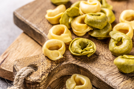 Homemade Tortellini with spinach, cheese and ricotta on wooden board. Gluten free italian food concept.の写真素材