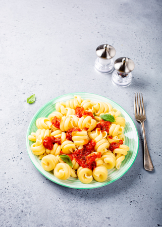 Vegetarian pasta Trattole with tomato sauce and basil on kitchen table background. Healthy italian food concept. Copy space.の写真素材