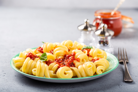 Homemade pasta Trattole with tomato sauce and basil on white plate. Delicious healthy italian vegetarian food background, copy space.の写真素材