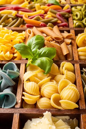 Spaghetti and assorted colorful italian pasta in wooden box. Healthy food background concept. Flat lay, top view.の写真素材
