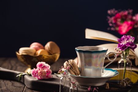 Cup of coffee, old books and pink carnation flowers on old wooden background. Mothers day, birthday greeting card. Copy space.の写真素材