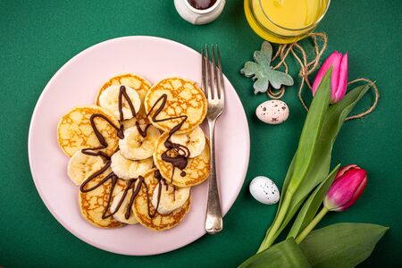 Healthy breakfast with fresh hot pancakes with bananas and chocolate on green background, top view.の写真素材