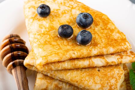 Delicious Tasty Homemade crepes or pancakes with blueberries, honey and mint on white plate. Healthy breakfast concept, gluten free. Copy space. High angle viewの写真素材