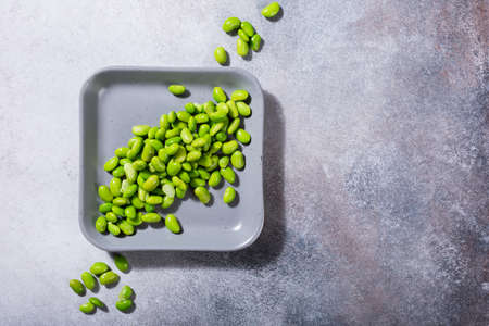 Green fresh soybeans on gray square plate on concrete background. Healthy food concept flat lay with coppy space. Top view.の写真素材