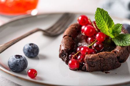 Hot chocolate pudding lava cake with fondant centre, red currants, bleuberry and mint leaves on gray...