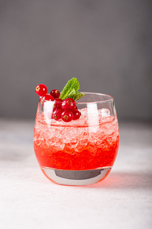 Fresh cocktail with crushed ice, red currant and mint on gray background. Summer cold drink concept...