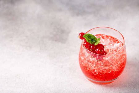 Fresh cocktail with crushed ice, red currant and mint on gray background. Summer cold drink concept with copy space. High angle viewの写真素材