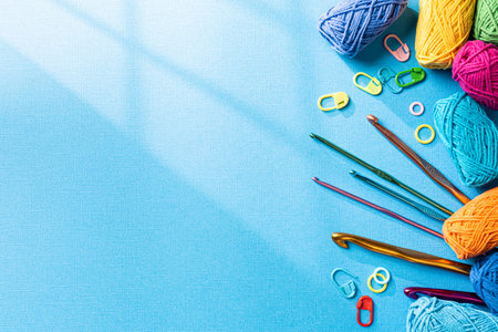 Crochet blue background with cotton yarn, crochet hooks and accessories. Flat lay overhead shot with copy space. Window shadowの写真素材